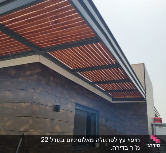 פרגולה מעץ מעל קיר חיצוני של מבנה